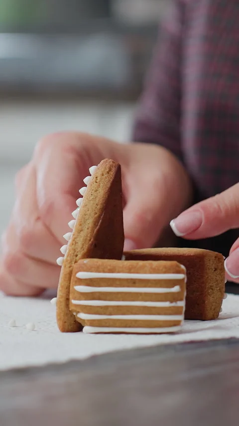 Lady using gingerbread cookies to design house with flower cookies and baking Stock Footage 320345878