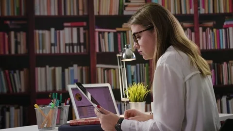 A Lady Using a Laptop and a Tablet in the Library Stock Footage 85040960