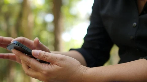 Lady using mobile phone over green garden background Stock Footage 100994258