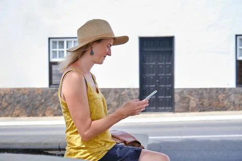Lady using mobile phone while sitting on street in sunshine Stock Photos