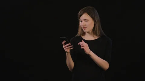A Lady Using a Phone Against a Black Background Stock Footage 87167868