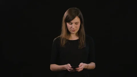 A Lady Using a Phone Against a Black Background Stock Footage 87172844
