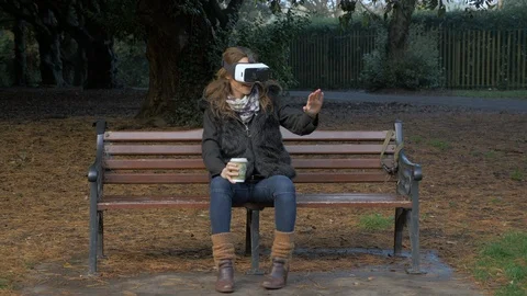 Lady With VR Set Sitting on A Bench In The Park Stock Footage 120408119