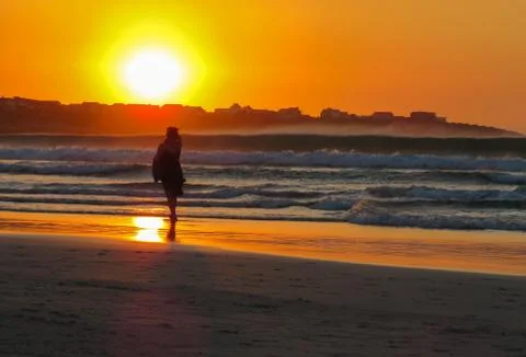 Lady walking on beach at sunset Stock Photos