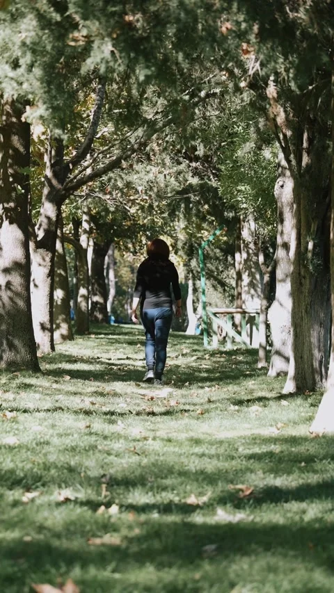 A lady walking in the park next to the tree Stock Footage 228827919