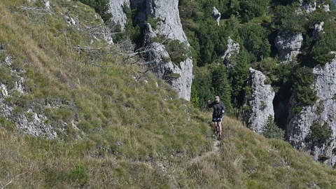 Lady walking up a rocky mountain path with hiking sticks Stock Footage 252583767