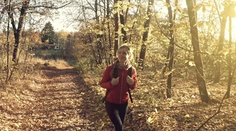 Lady walks on the forest path at sunny autumn day 스톡 동영상 57362992