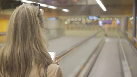 Lady walks through train station on phone. Stock Footage 82328587