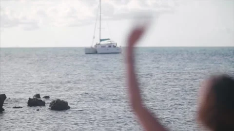 Lady waves at Catamaran from the shore. Stock Footage 159723117