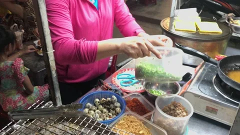 Lady wearing mask grilling bread at a street vendor, Hoi An old town at night Stock Footage 142244986