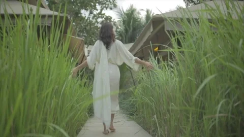 Lady in white robes walks down a tall isle of grass. Stock Footage 82329264