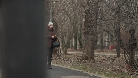 Lady in winter coat exploring urban park. Female visitor clad in insulated Stock Footage 345552564