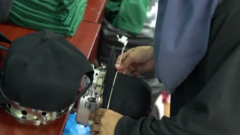 A lady worker framing a black cap for embroidery machine use. Stock Footage 217445866