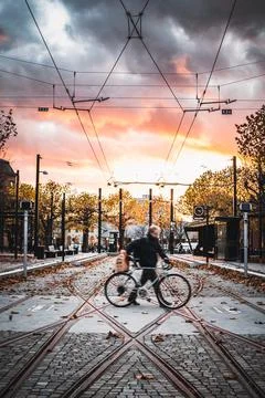 Lady working fast over tram tracks when the sun slowly rises in the morning Stock Photos