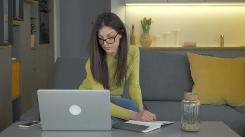 A Lady Working From Home, Working On Laptop And Writing On Her Notebook Video stock 128366191