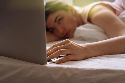Lady working remotely while lying in bed talking on a video call Stock-Fotos
