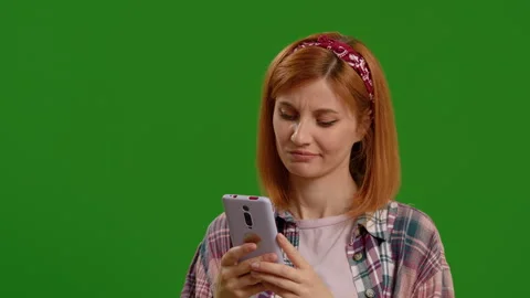 Lady working on smartphone or scrolling looking suspiciously on green screen Stock Footage 299652774