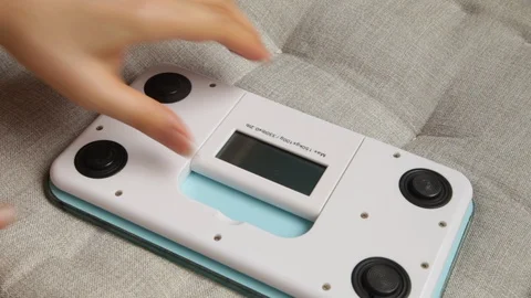 Lady's hands replacing a battery in electronic scales Stock Footage 129030838