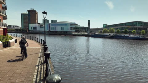 Lagan River Towpath with cyclists. Waterfront Hall across river Stock Footage 335836070