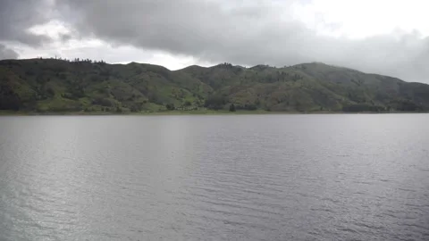 Lagoon surrounded by fog on a cloudy day, surrounding Andean mountains Stock Footage 277468741