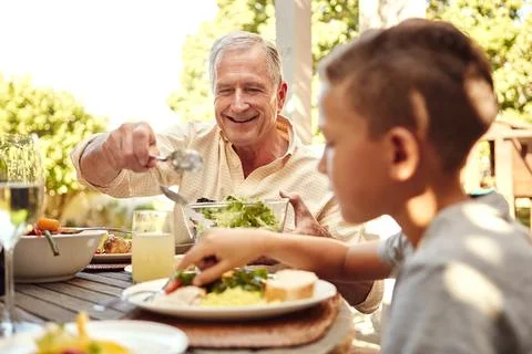 Laid back Sunday lunch with the family. a family eating lunch together outdoors. Stock Photos