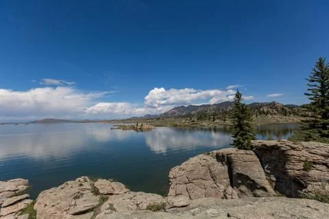 Lake and clouds reflection with rocky mountains and forest Stock Photos