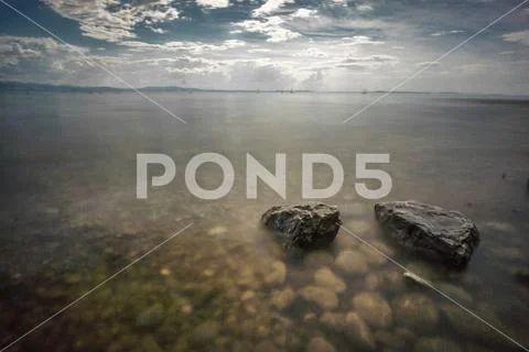Lake constance summertime shore rocks in water cloud Stock Photos