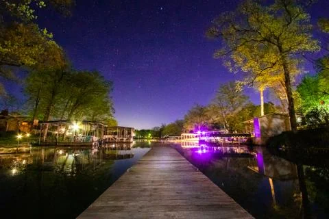 Lake Cove at Night with Dock Neon Lights and Stars Stock Photos
