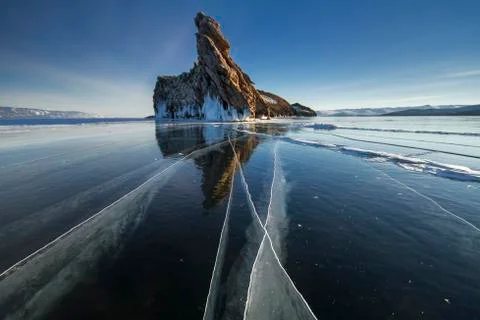 Lake is covered with a thick layer of ice. Ice story. Stone rock sticking o.. Stock-Fotos