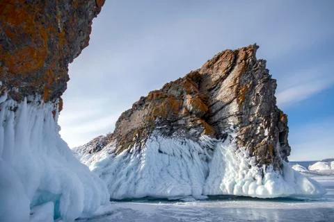 Lake is covered with a thick layer of ice. Ice story. Stone rock sticking o.. Stock Photos