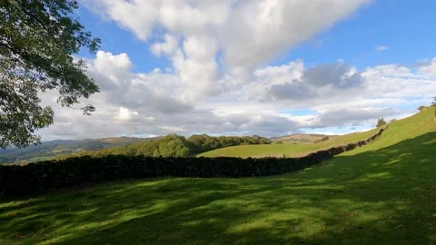 Lake District grass field stone wall fells trees clouds Video stock 219047278