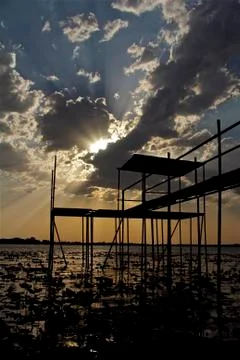 Lake Dock with sun hidden in clouds Stock Photos