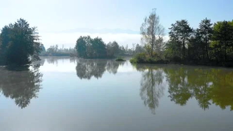 Lake at the edge of the mountains with forest reflected in the clear water Vídeo Stock 150558796