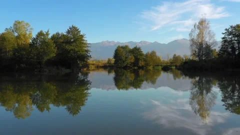 Lake at the edge of the mountains with forest reflected in the clear water Vídeo Stock 150558896