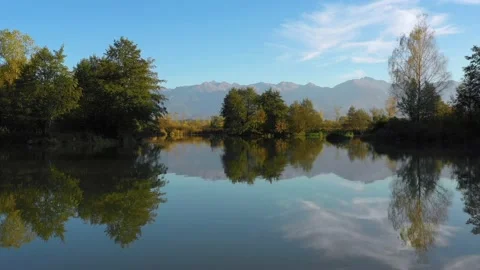 Lake at the edge of the mountains with forest reflected in the clear water Stock Footage 150558924