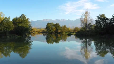 Lake at the edge of the mountains with forest reflected in the clear water Video stock 150558950