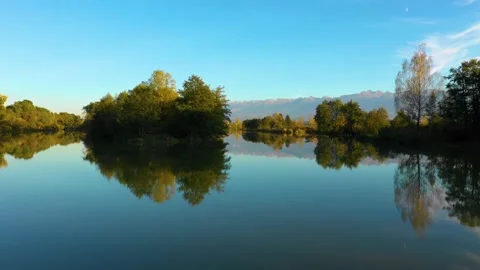 Lake at the edge of the mountains with forest reflected in the clear water Video stock 150600624