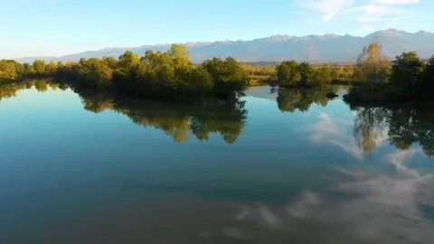 Lake at the edge of the mountains with forest reflected in the clear water 스톡 동영상 150609234