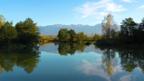 Lake at the edge of the mountains with forest reflected in the clear water Video stock 150609486