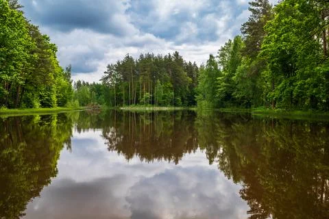 The lake in the forest under storm clouds. Stock Photos