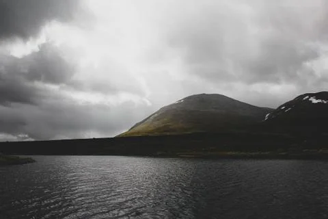 Lake in front of cloudy mountains Stock Photos