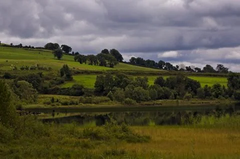 Lake in green fields Stock Photos