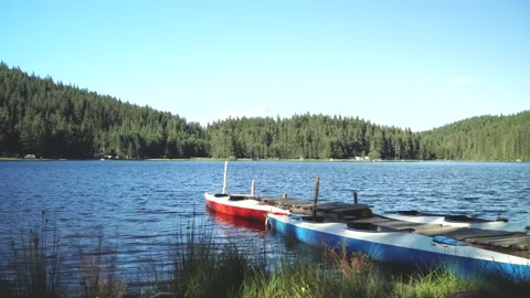 Lake high in the mountains. In the foreground a quay with several kayaks Stock Footage 138943495