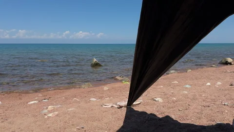 Lake Issyk-Kul view from a protective sun tent on the sandy beach Stock Footage 342034622