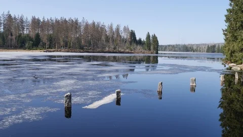 Lake with last ice and steles in sunny mountain range Harz spring season Stock Footage 88361237