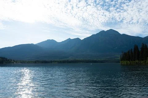 Lake with mountain backdrop beneath a sky filled with clouds Stock Photos