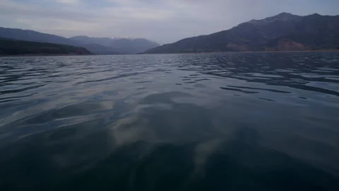 Lake in the mountains, camera at the water surface. taken from a boat in motion Stock Footage 241500717