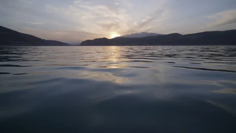 Lake in the mountains, camera at the water surface. taken from a boat in motion Stock Footage 241501102