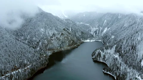 Lake in the mountains surrounded by forest in winter season. Flying above Stock Footage 152010615