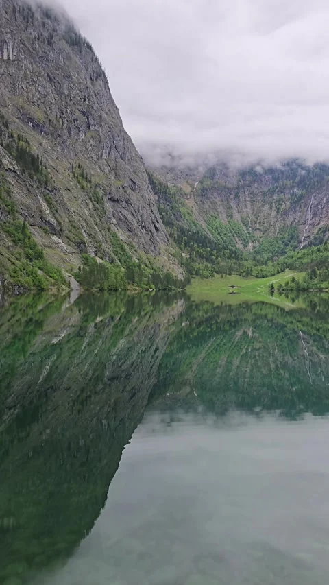 Lake Obersee reflects alpine cliffs and green slopes in the Bavarian Alps.  Stock Footage 309417671
